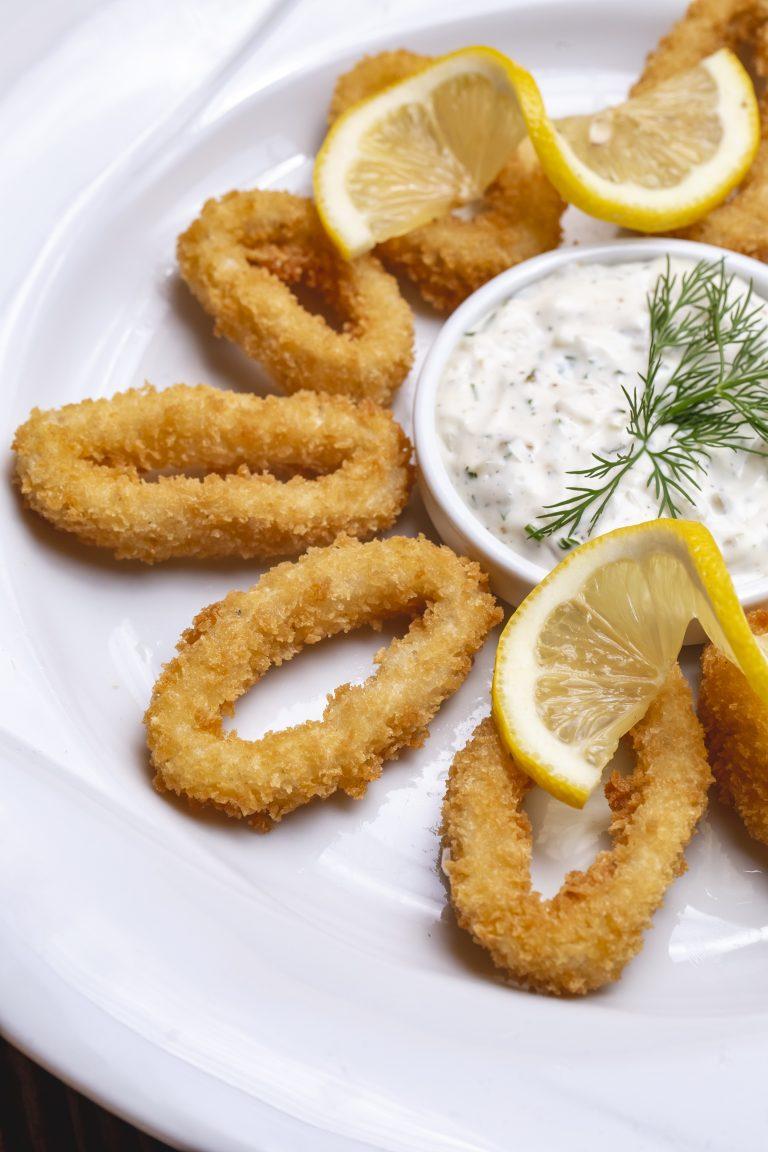 fried calamary in breadcrumbs lemon tartar sauce dill side view